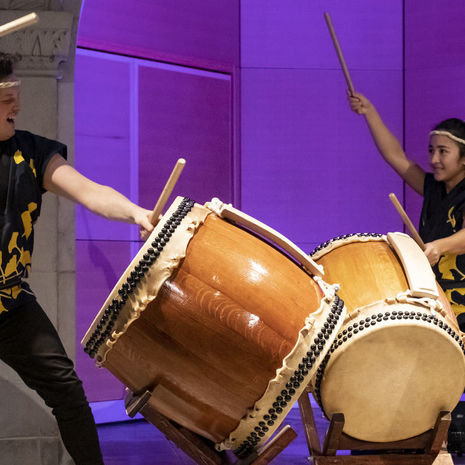 wo students banging on drums as part of a Taiko performance. 