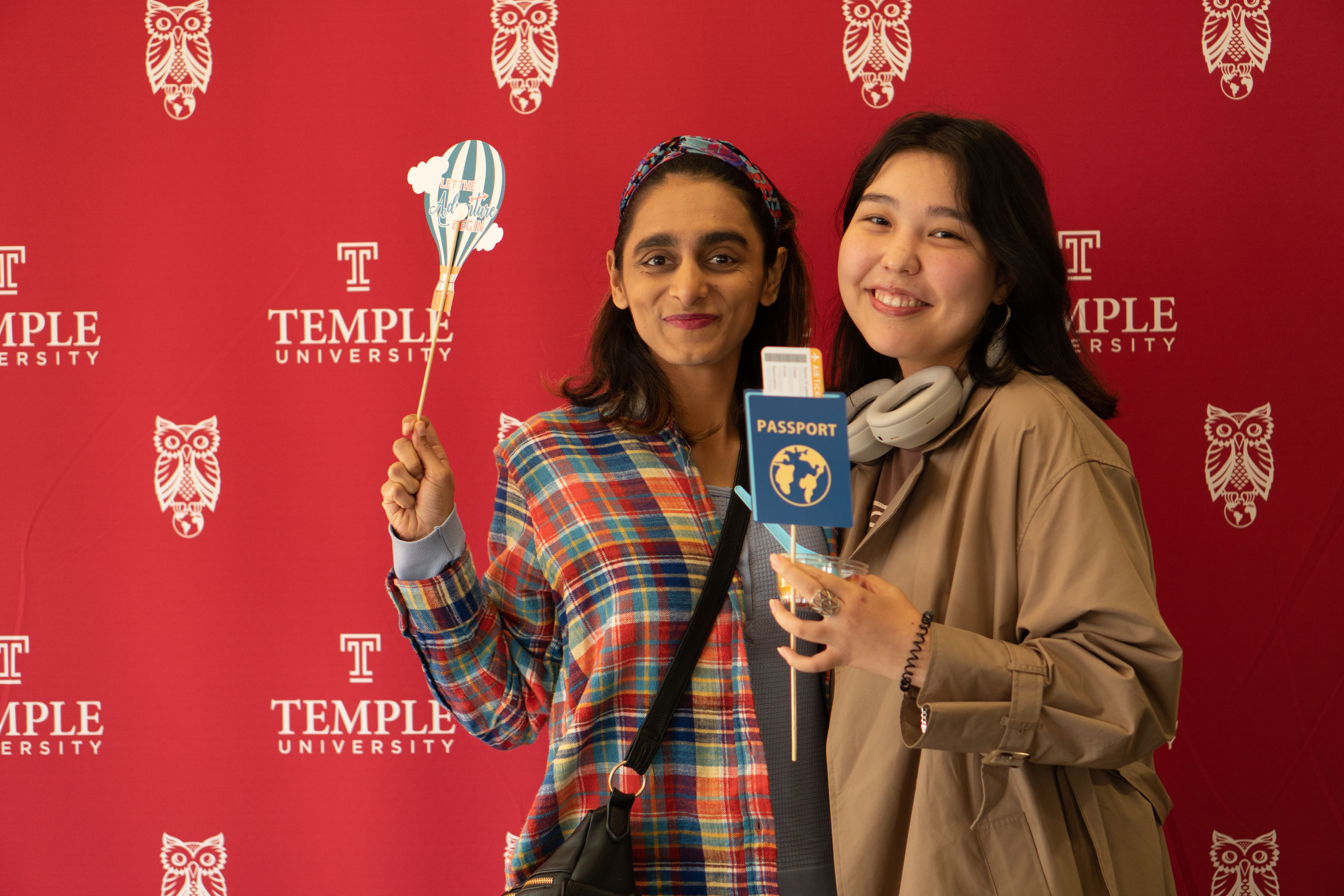 Two students smiling into the camera and holding globally themed props.