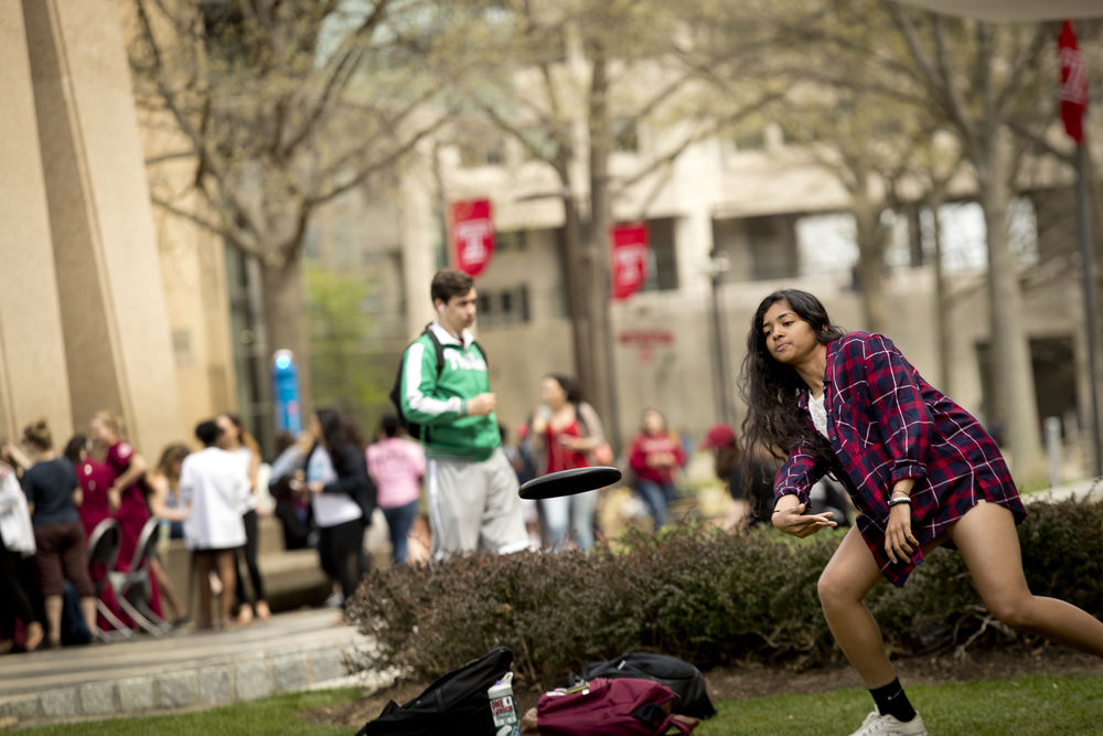 temple student playing frisbee on lawn