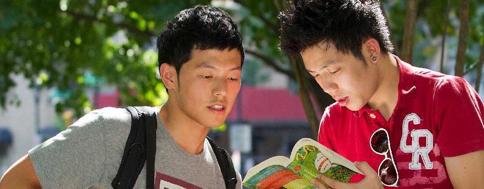 two male students reading a book
