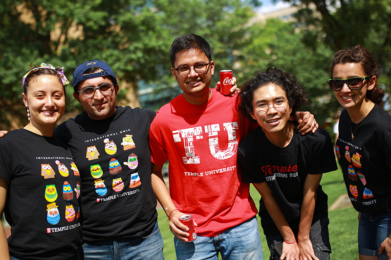 Five Temple students in black and red Temple T-shirts smiling at the camera